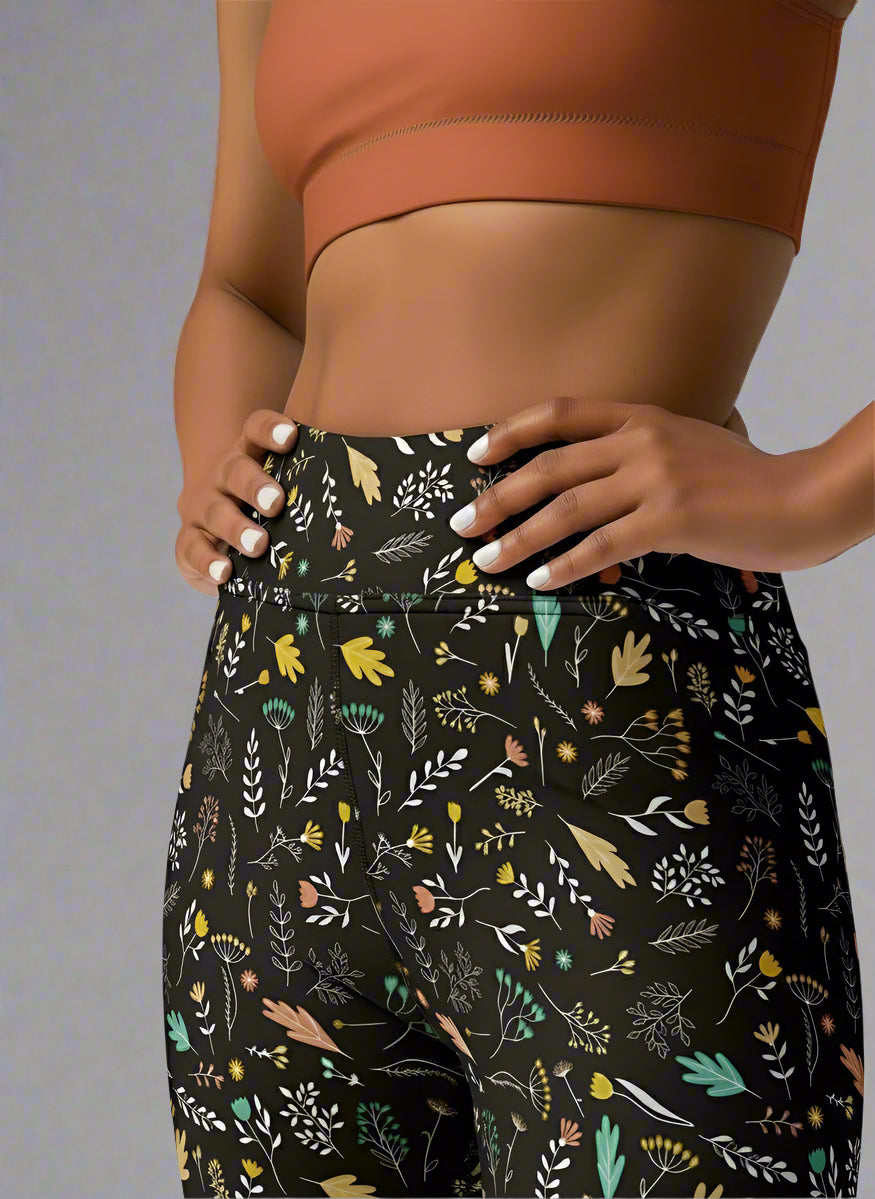 Front, close view of person wearing a brown sports bra and black floral pants on a gray background