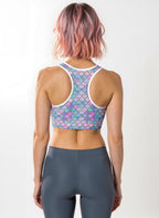 Person wearing a colorful patterned sports bra and gray leggings on a white background