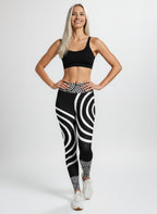 Woman wearing black and white patterned leggings with a plain background