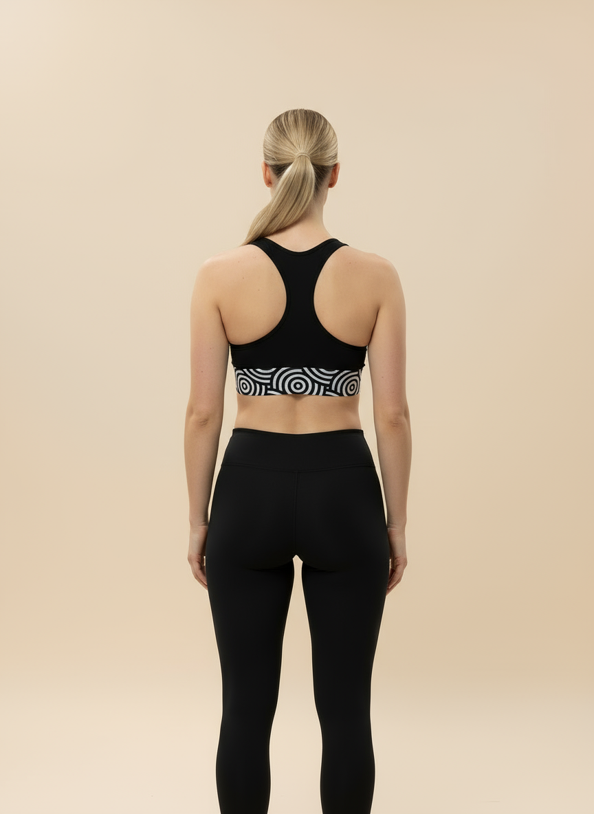 Person wearing a black sports bra with a unique pattern and black leggings on a beige background