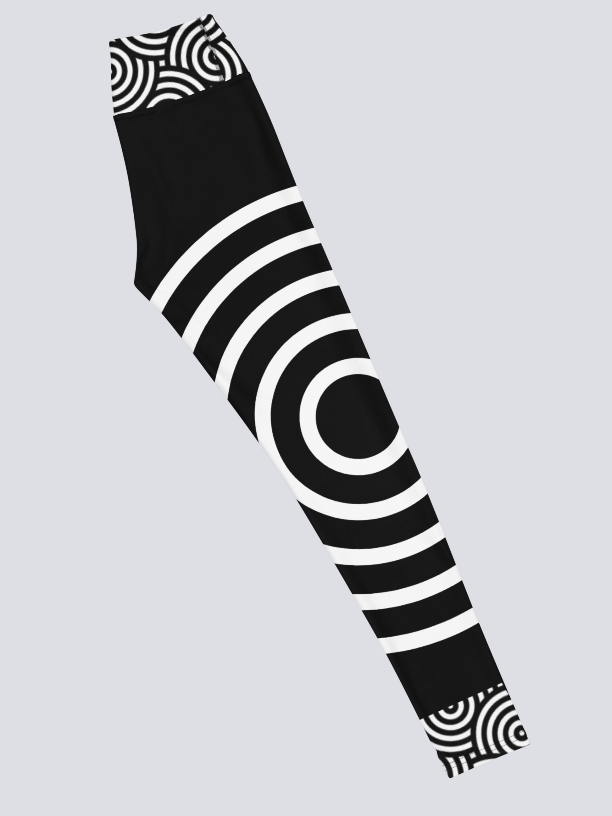 Right‑side view of black high‑waisted Lunar Loops yoga leggings with bold white concentric circle pattern, featuring large circular motif on thigh and smaller circles near waistband and ankle for a striking, modern look.