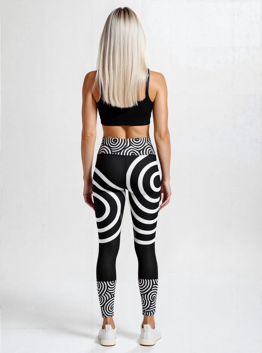 Back view of a woman wearing Lunar Loops Yoga leggings with striking black and white concentric circle print and a black sports bra, standing against a plain light background.