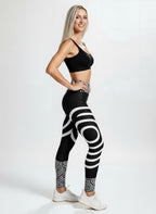 Woman wearing black and white patterned leggings with a sports bra on a white background