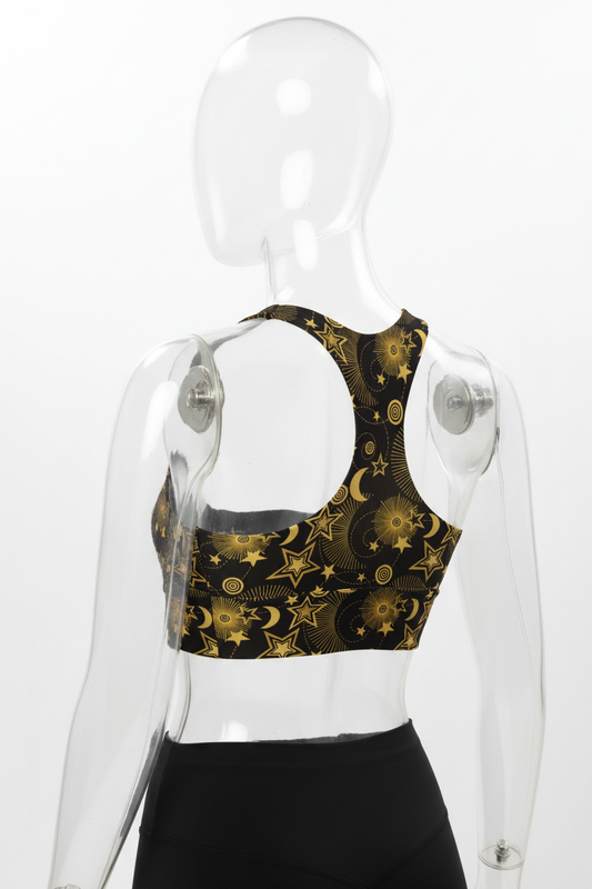 A clear mannequin shown from the back wearing a black sports bra with a gold celestial pattern of stars and crescent moons, paired with black leggings, against a plain white background.