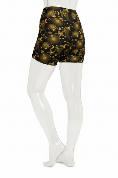 A mannequin wearing high-waisted black shorts with a gold celestial print of stars, moons, and planets, shown from the waist down against a plain white background.