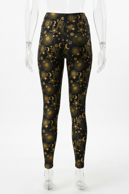 A mannequin from the back wearing high-waisted leggings with an allover celestial print of gold stars, crescent moons, and glowing orbs on a black background, against a plain white studio backdrop.