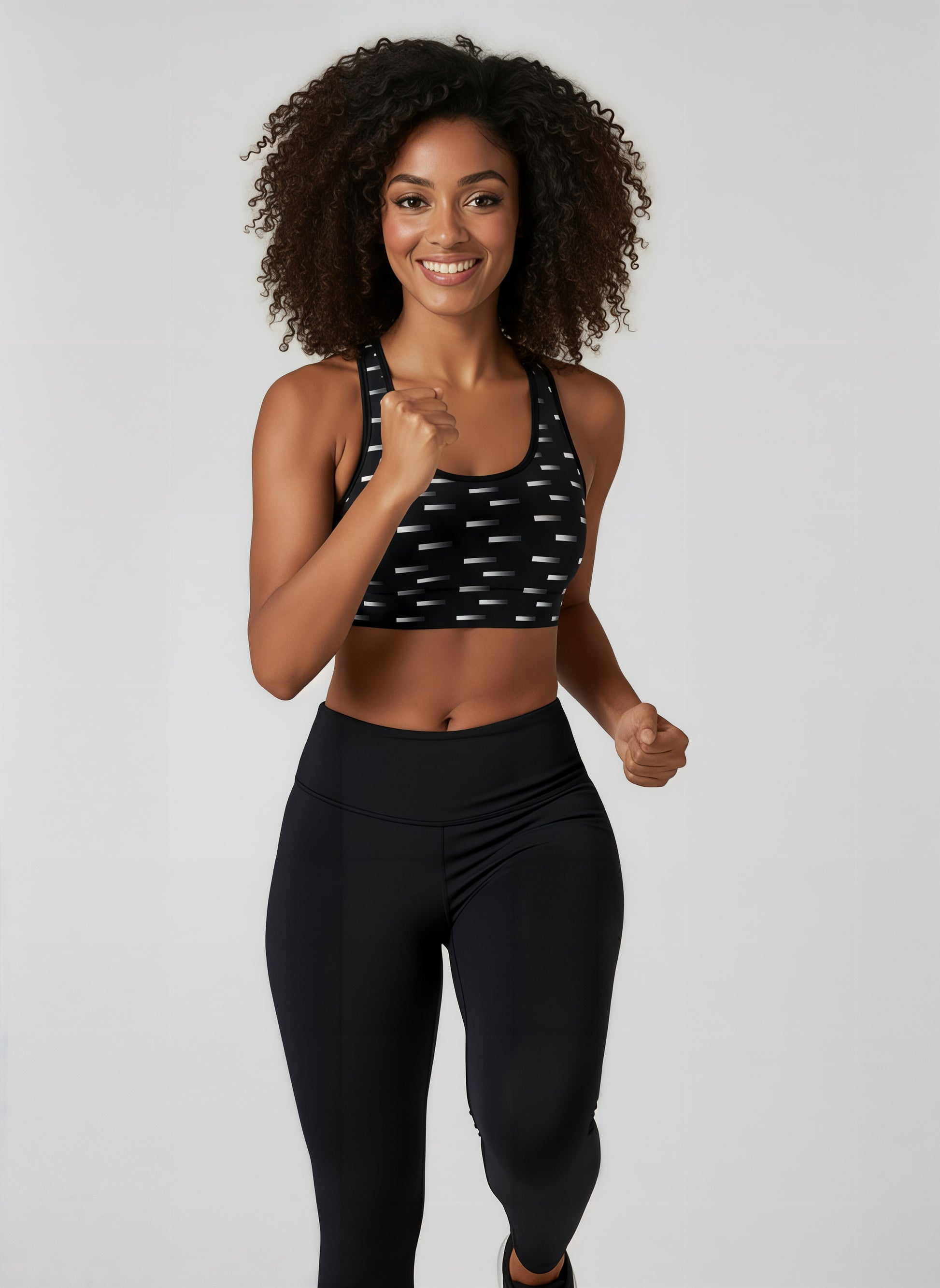 Woman wearing a black sports bra and leggings with a white background