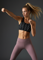 Woman in athletic wear posing against a dark background