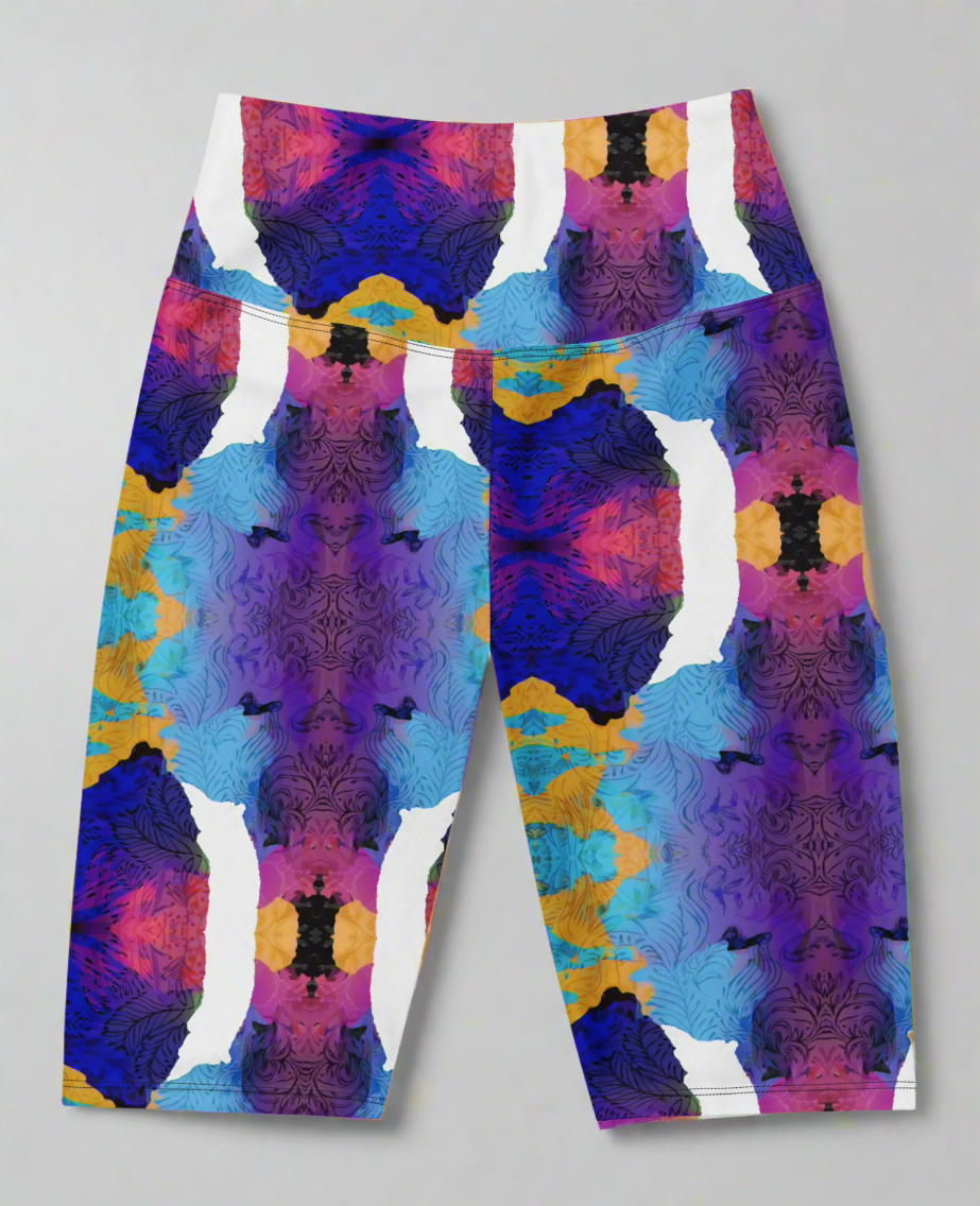 Front view, flat-lay of Ocean Mirage Biker Shorts featuring a vibrant abstract pattern in deep blue, purple, pink, orange, black, and white; displayed flat against a neutral grey background to highlight the bold kaleidoscopic design.