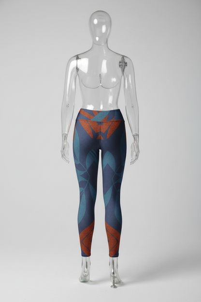 A mannequin shown from the back wearing high-waisted leggings with an abstract geometric pattern in navy blue, teal, and rust orange, standing barefoot against a white background.