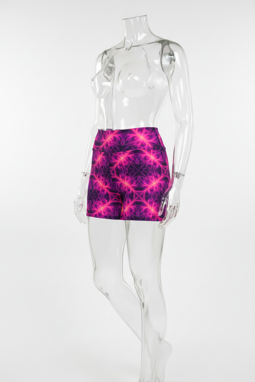 A mannequin wearing high-waisted athletic shorts with a vivid neon fractal pattern in hot pink, magenta, and purple on a black background, shown against a plain white studio backdrop.