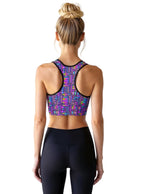 Woman wearing a colorful sports bra and black leggings on a white background