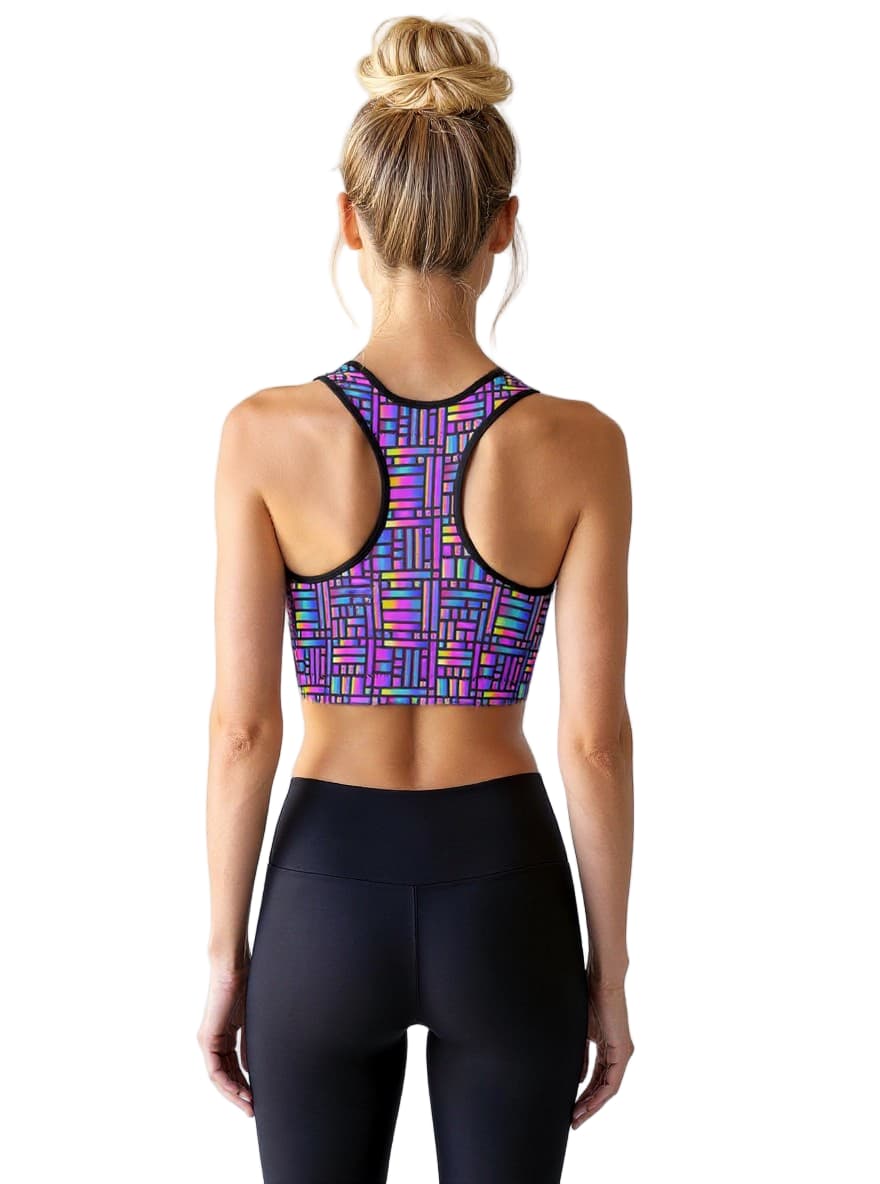 Woman wearing a colorful sports bra and black leggings on a white background