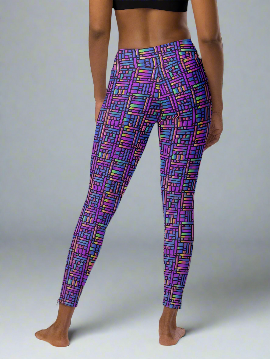 Back view of woman wearing Pixel Pulse Yoga leggings with vibrant multicolored geometric pattern in purple, pink, blue, green, and yellow, paired with a black sports bra, barefoot against a plain gray background.