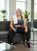 Woman in colorful zebra-patterned workout outfit sitting on a couch holding a water bottle.