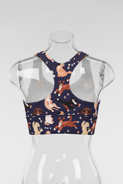 A women's sports bra with a navy blue base featuring a playful print of various dog breeds and white bones, shown against a plain white background. 