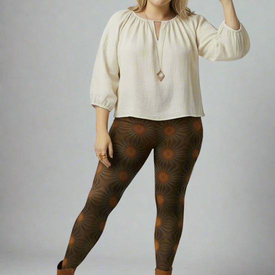 Women’s Rustic Amber yoga leggings brown radial geometric print styled with a cream long-sleeve keyhole blouse, wide-brim brown hat and brown ankle boots against a pale backdrop.