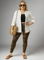 Woman wearing a white shirt, black top, brown patterned leggings, and sandals on a gray background