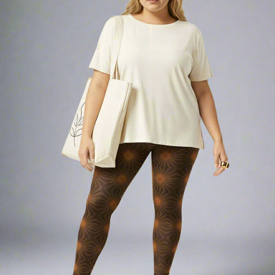 Women’s Rustic Amber yoga leggings, brown with amber geometric starburst print, paired with a cream tee, white sneakers and cream tote against a pale gray backdrop.