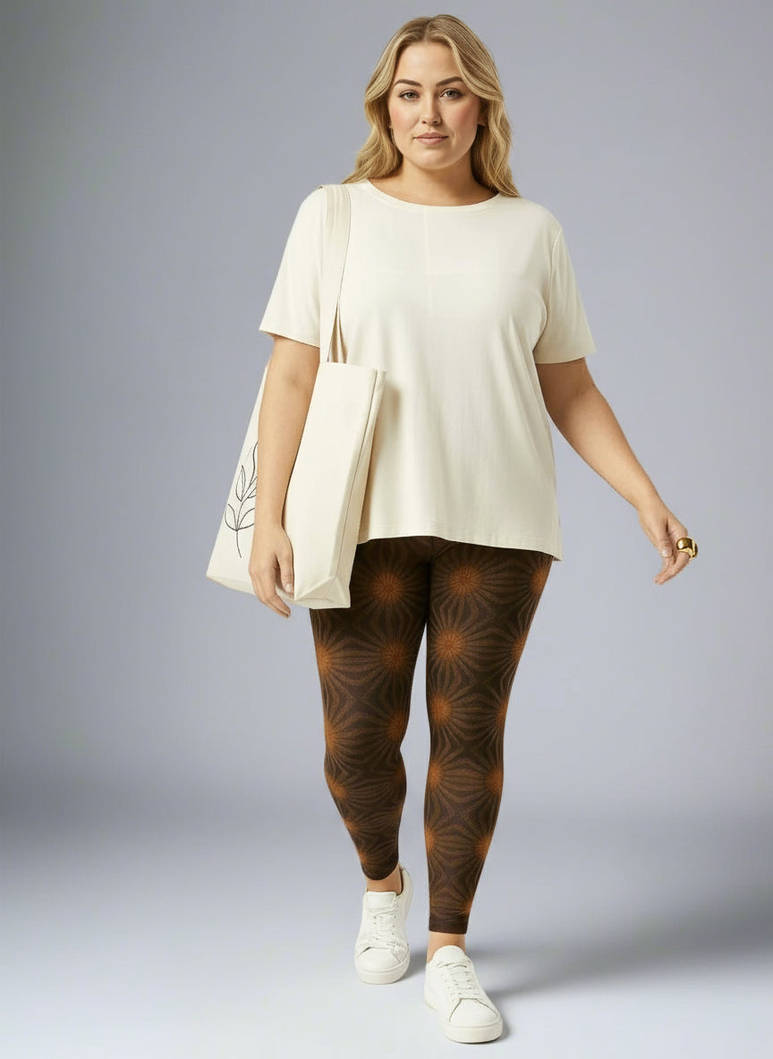 Women’s Rustic Amber yoga leggings, brown with amber geometric starburst print, paired with a cream tee, white sneakers and cream tote against a pale gray backdrop.