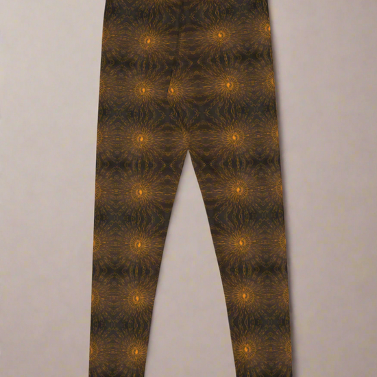 Back-flat product image of Rustic Amber leggings showing the full front panel and high-rise waistband, symmetrical mirrored brown and black kaleidoscope pattern with regularly spaced glowing orange circular motifs, full-length silhouette on a neutral background.
