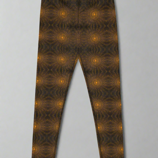  Front-flat product image of Rustic Amber leggings showing the full front panel and high-rise waistband, symmetrical mirrored brown and black kaleidoscope pattern with regularly spaced glowing orange circular motifs, full-length silhouette on a neutral background.
