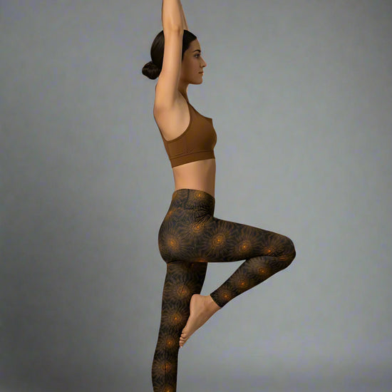 Person wearing a brown sports bra and patterned leggings performing a yoga pose on a gray background