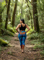 Woman walking in a forest wearing colorful leggings and a black top.