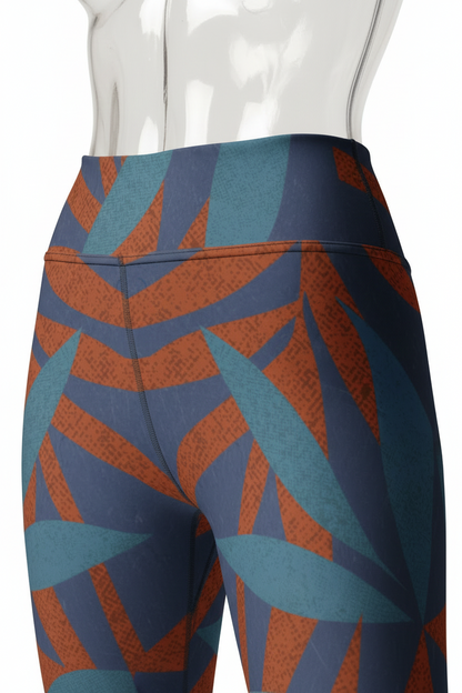 Close-up of a mannequin wearing high-waisted leggings with a geometric leaf pattern in blue, teal, and rust orange, paired with a beige sports bra against a white background.