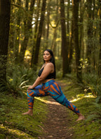 Woman in colorful leggings and black top standing in a forest
