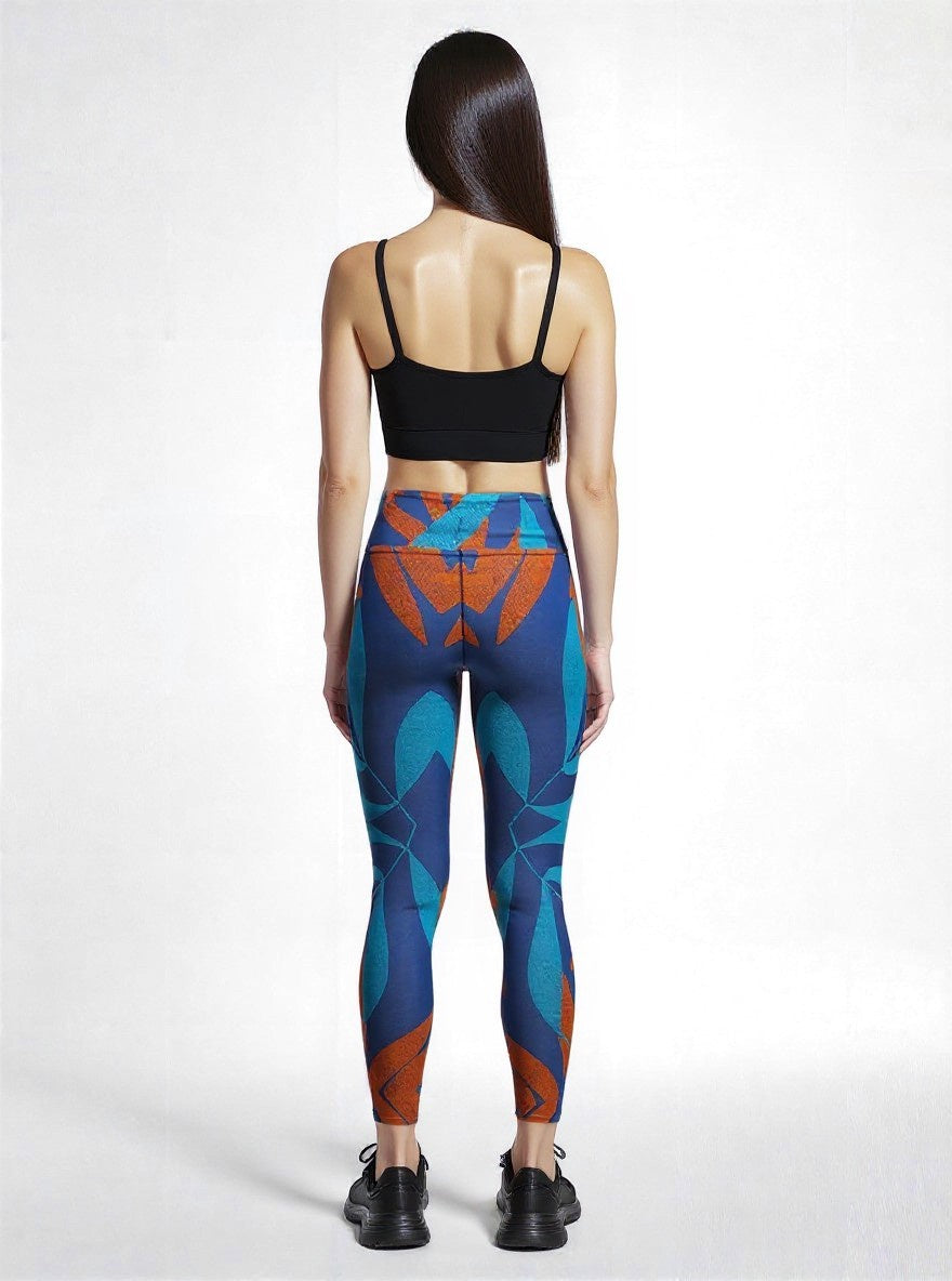 Back view of a model wearing Pixie & Sherbet’s Rustic Rhythm Yoga leggings featuring a bold geometric print in teal, orange, and blue tones, paired with a black crop top and black sneakers, set against a clean white background.
