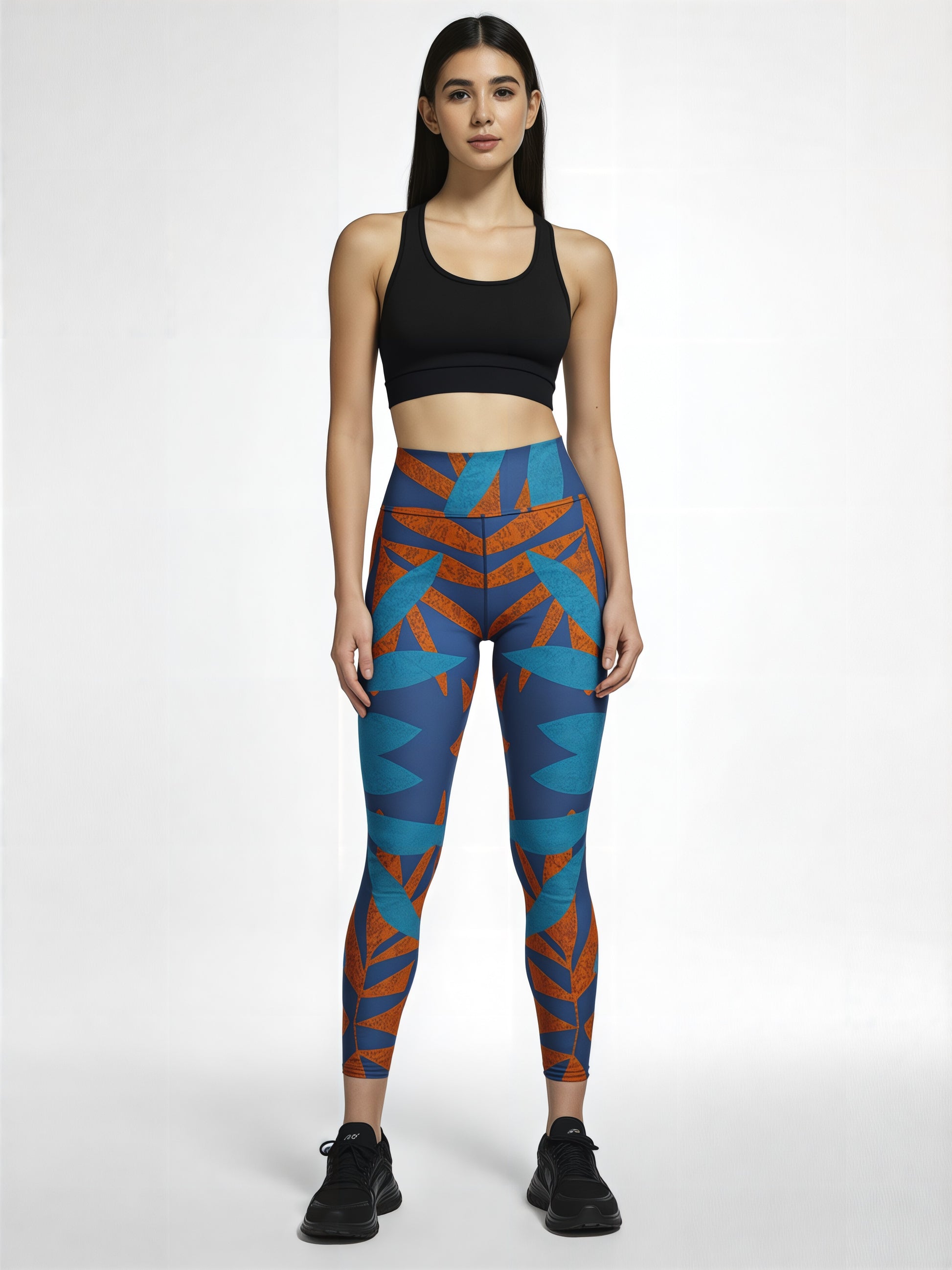 Model wearing Pixie & Sherbet’s Rustic Rhythm Yoga leggings with a vibrant blue and orange angular print, paired with a black sports bra and black sneakers, standing confidently against a white background