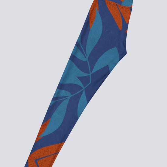 Left side of blue and burnt orange patterned yoga legging on a light grey background