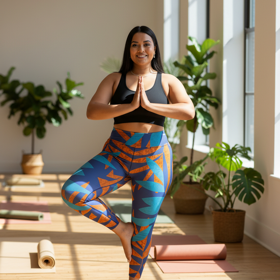 Woman in colorful yoga pants standing on one leg in a well-lit room with plants