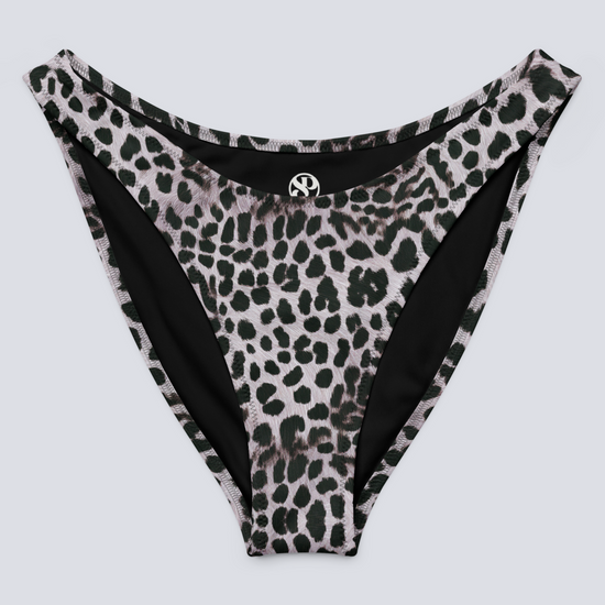 Flat-lay of Savannah Charge Cheeky Bikini Bottoms in monochrome leopard print with high-cut silhouette and Pixie & Sherbet logo detail – bold, sculpting swimwear.