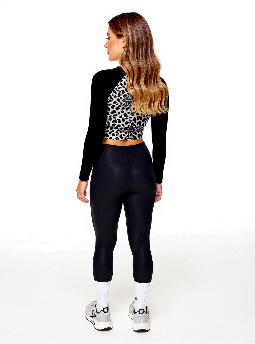 Back view of model in Savannah Charge Surf Crop Top featuring black and white leopard print and solid black sleeves, styled with black leggings and white sneakers with pink accents; posed against white backdrop.