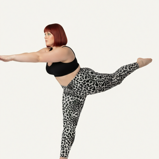 Person wearing black tank top and leopard print leggings on a white background