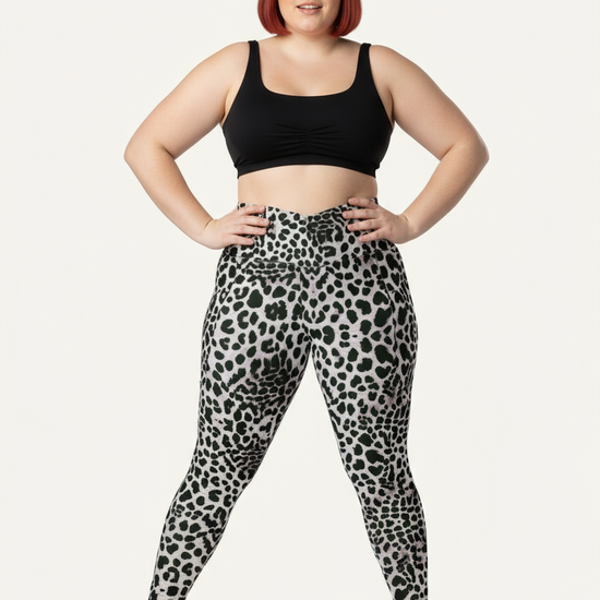 Person wearing black tank top and leopard print leggings on a white background