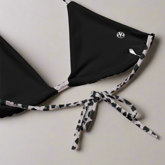 Empowering black triangle bikini top with bold Savannah Charge print straps, luxe logo accent, and adjustable tie-back fit—styled on a clean backdrop for modern contrast