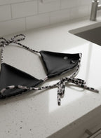 Black bikini with leopard print straps on a white countertop