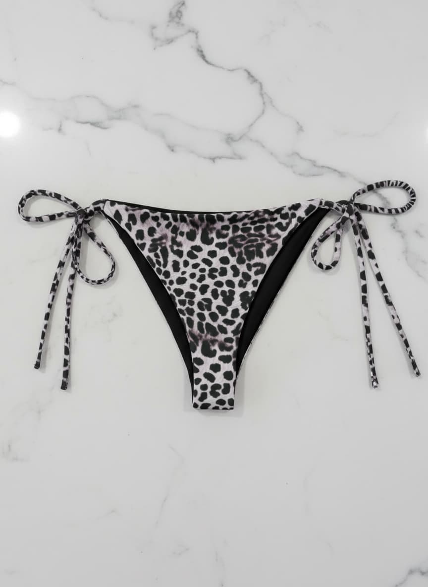 Leopard print bikini bottom with ties on a marble surface