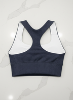Navy sports bra with white mesh panels on a white background