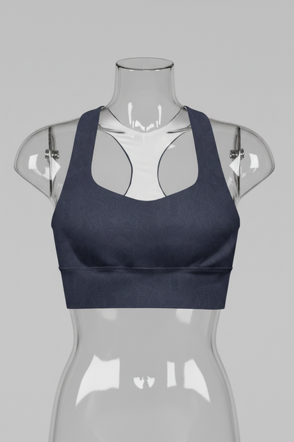 A women's sports bra in dark navy blue with a subtle tonal geometric pattern, featuring a white inner lining and racerback-style straps, shown against a plain white background. 