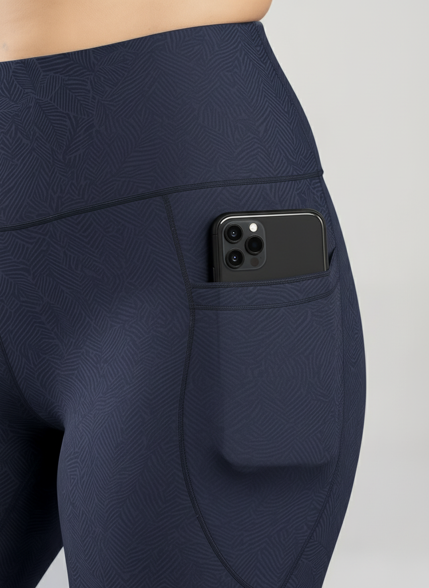 Navy blue leggings with a pocket holding a smartphone on a light gray background