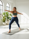 Woman practicing yoga in a bright, minimalistic room with plants.