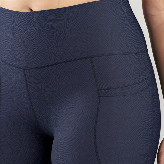 "Close-up of the high-waisted Shadowleaf Pocket Leggings in navy blue, showing the subtle leaf pattern and a side pocket detail.