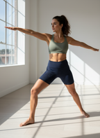 Woman in athletic wear performing a yoga pose in a bright room with large windows.