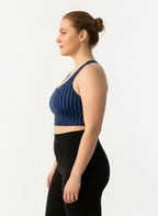 Woman wearing a blue striped sports bra and black leggings on a white background
