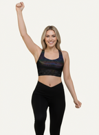 Woman wearing a black sports bra with colorful patterns on a white background