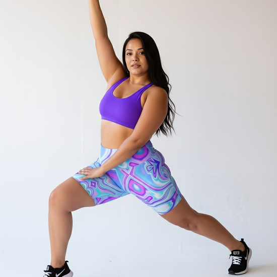 Woman in purple sports bra and patterned shorts posing against a white background